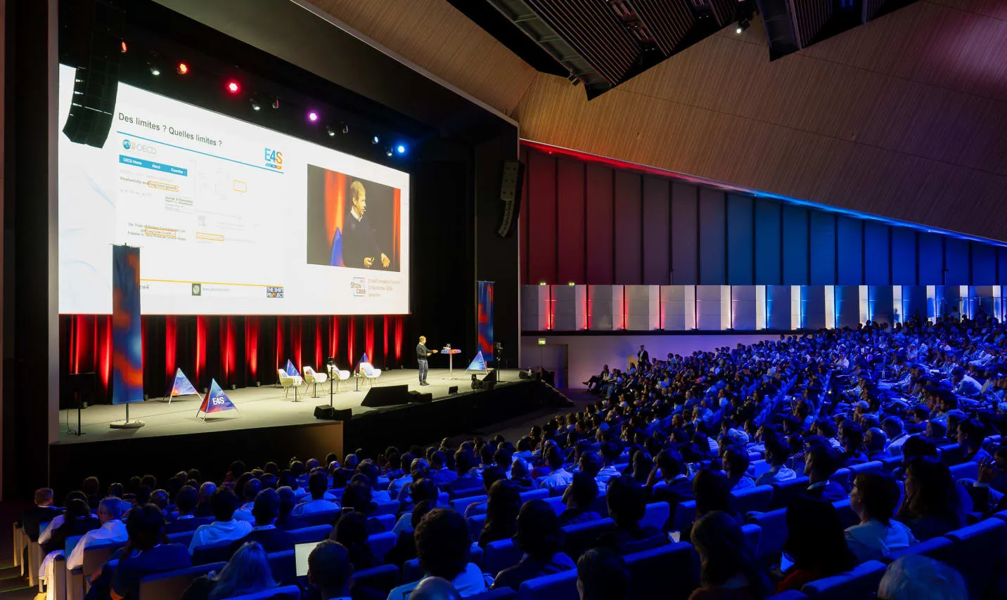 Salle plénière pleine face à la scène aux triangles, Showcase E4S 2025