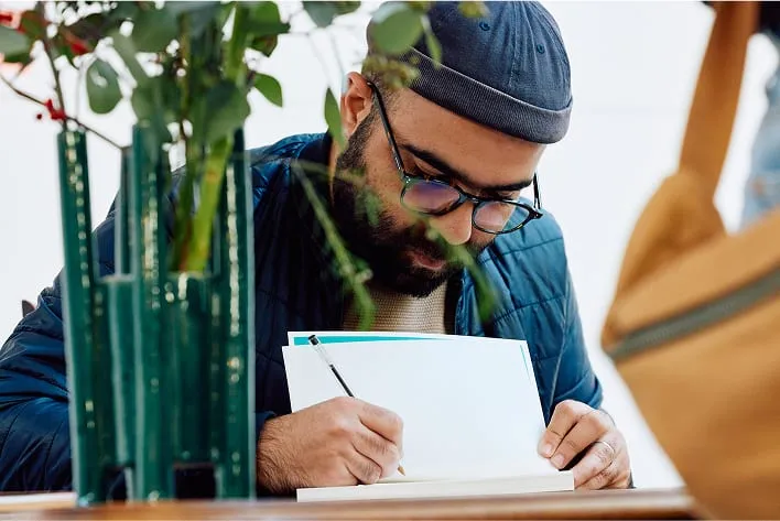 A man sitting at a table writing on a piece of paper