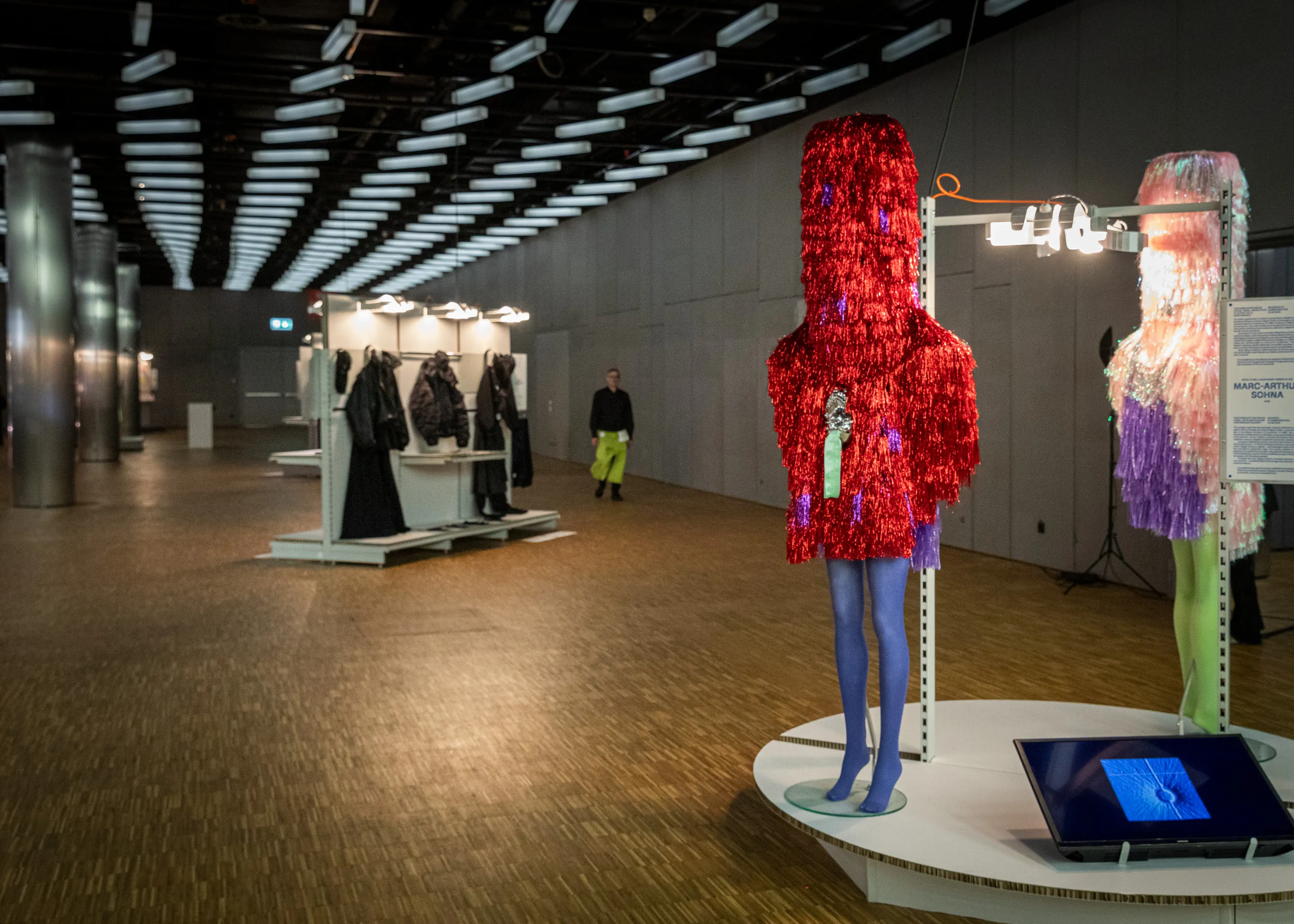 Red and silver costumes displayed on a round plinth.