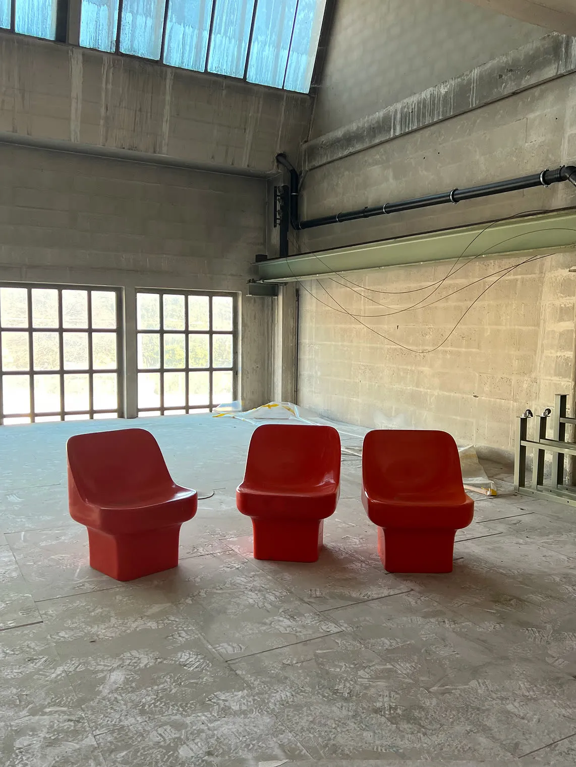 Trois fauteuils rouges assis dans une grande pièce