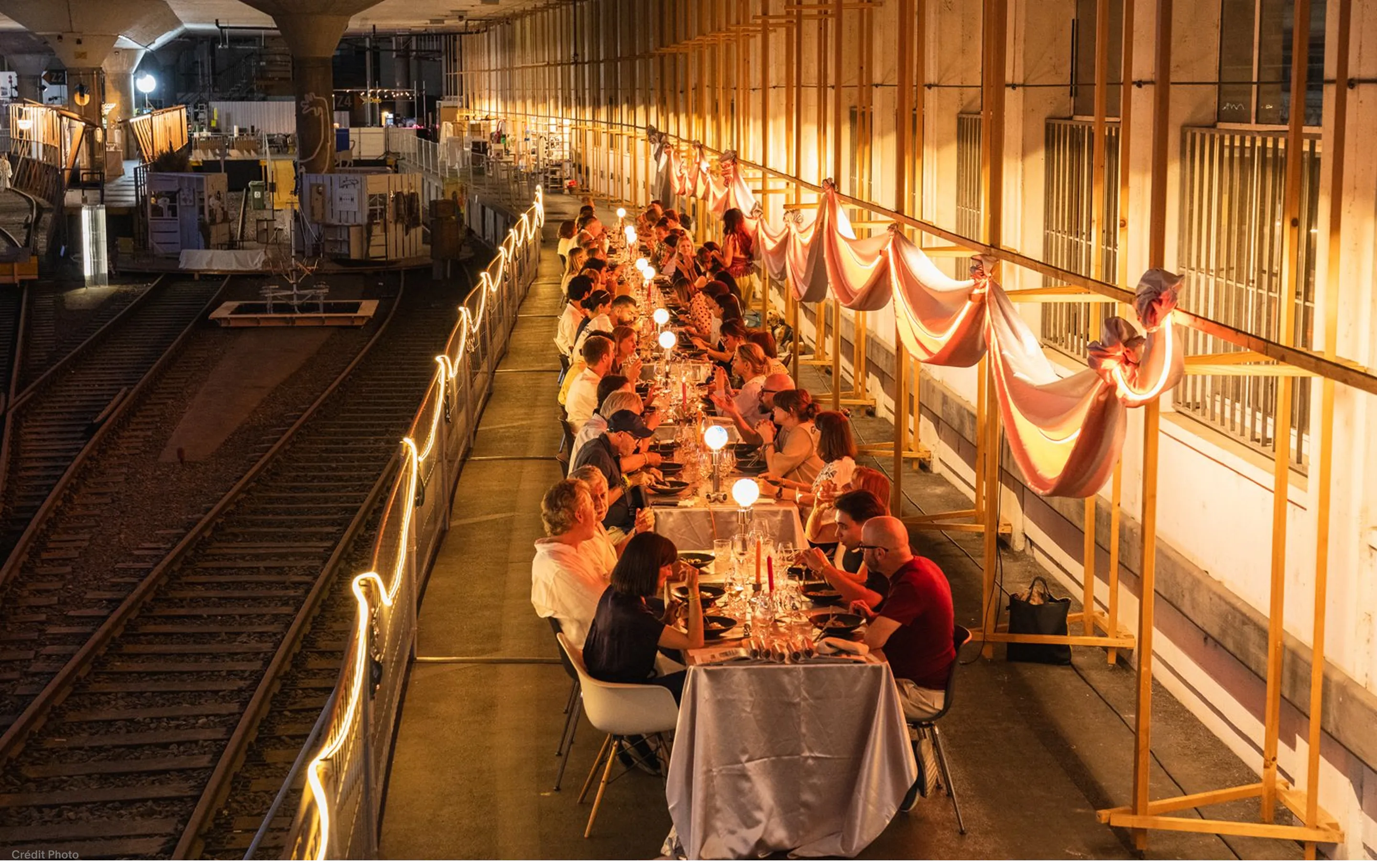 Longue table du Design Dinner le long des voies ferrées, sous des drapés roses