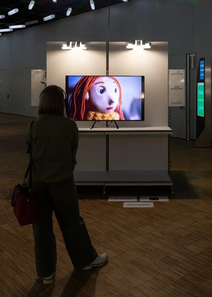 A visitor in front of a screen showing an animated character.