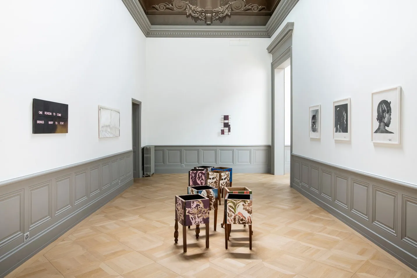 Salle aux murs blancs avec sculptures au sol et photographies encadrées, Palais de l'Athénée