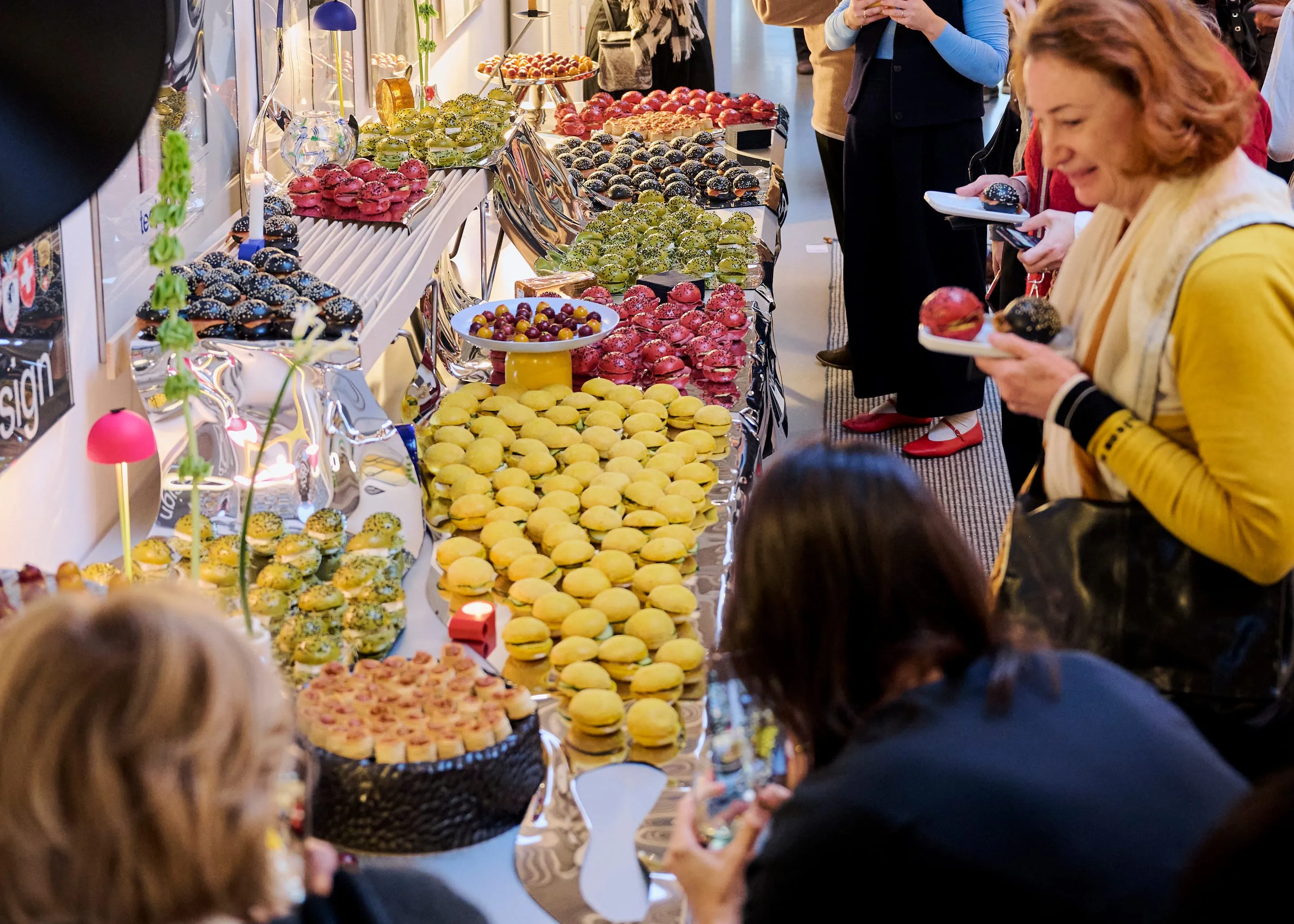 Invité·e·s autour du buffet des chefs V-Zug, dressé sur des surfaces miroir thermoformées, showroom Teo Jakob