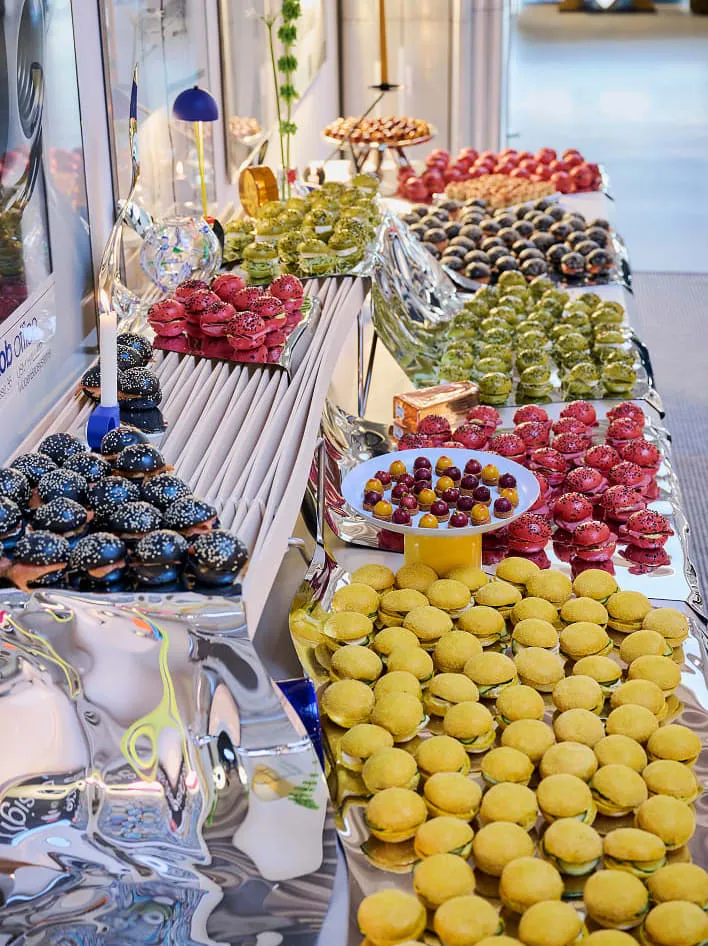 Long buffet de macarons, bouchées et fleurs sur des surfaces miroir