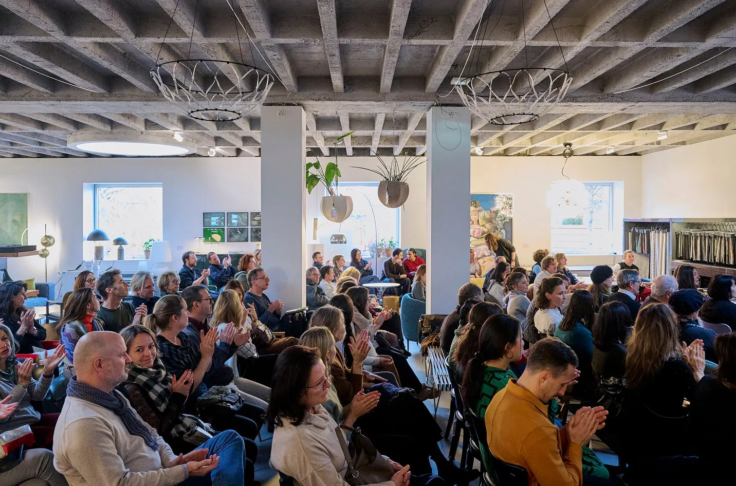 Public applaudissant sous le plafond en béton à caissons du showroom Teo Jakob