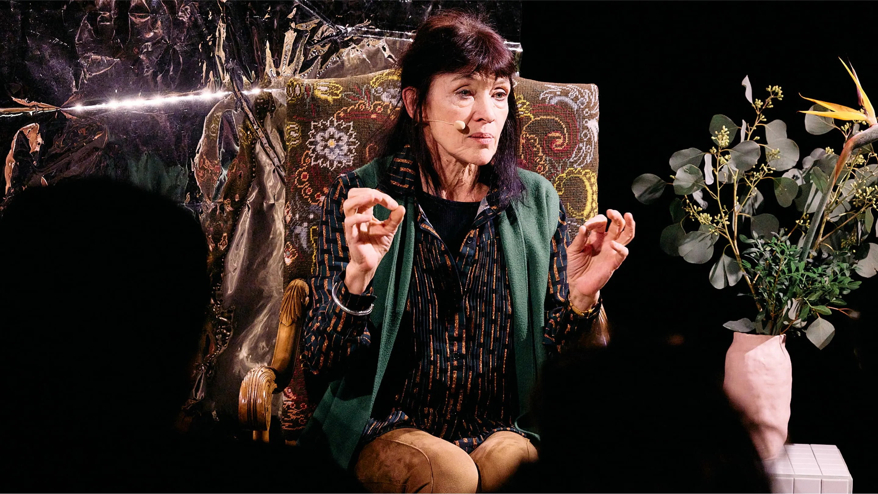 Nancy Huston giving a talk, vase and flowers.