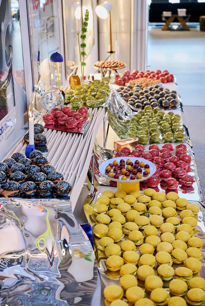Long buffet de macarons, bouchées et fleurs sur des surfaces miroir