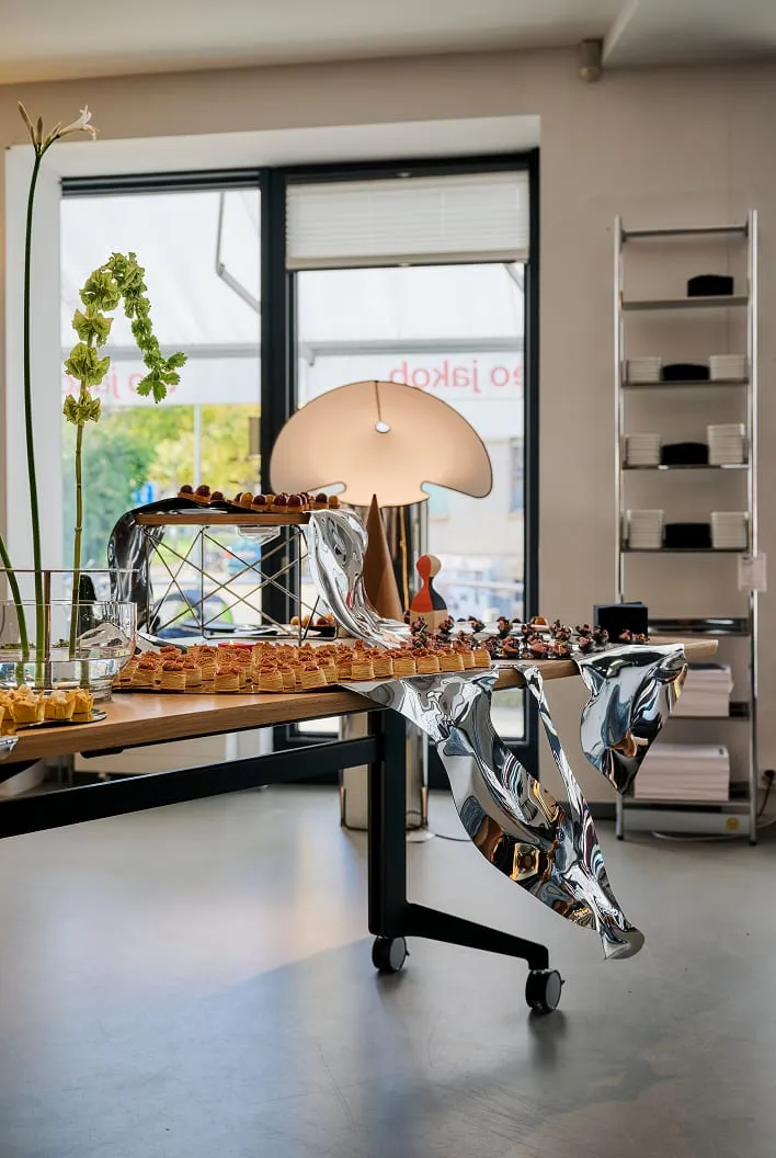 Table de bouchées devant une vitrine Teo Jakob, surface miroir drapée sur le bord