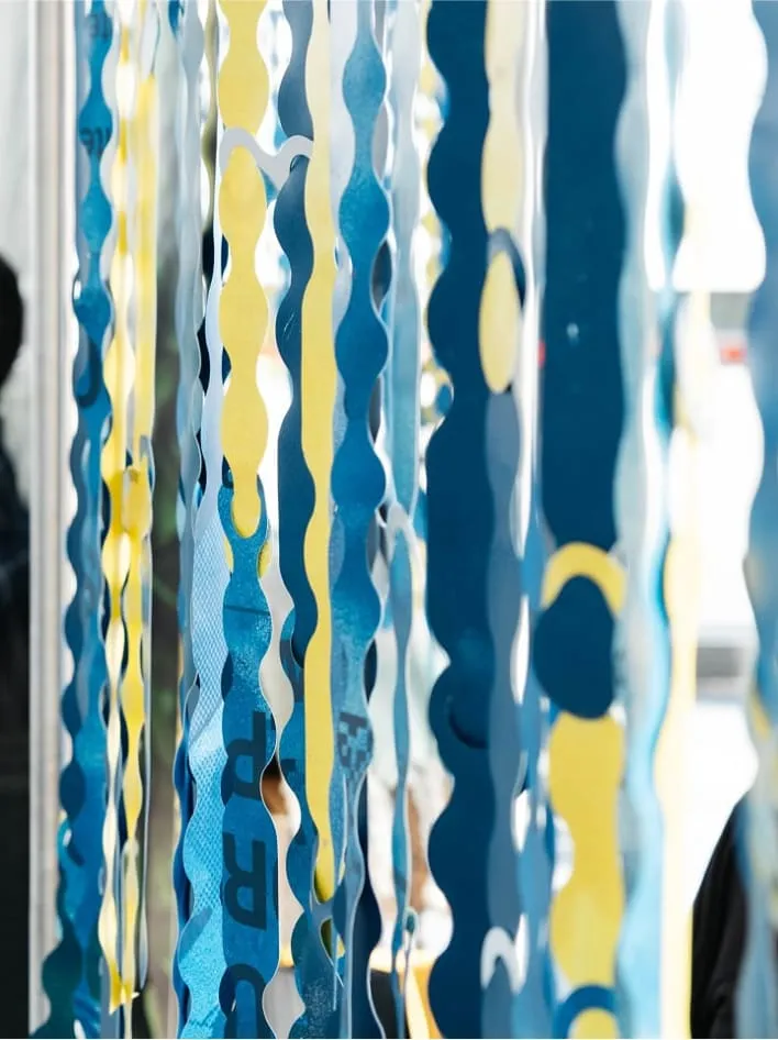 Participant·e·s assis près d'un rideau modulaire bleu et jaune