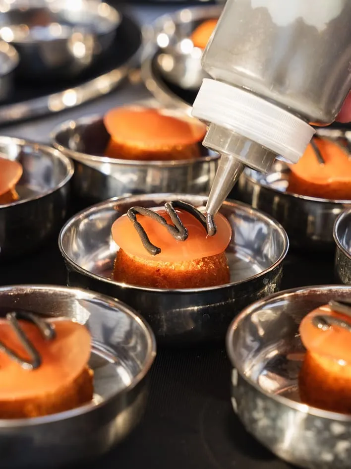 Desserts ronds dans des moules en métal, garnis à l'aide d'un flacon