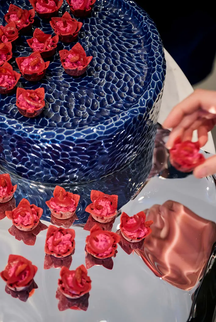 Tartelettes roses et rouges sur un présentoir bleu et une surface miroir