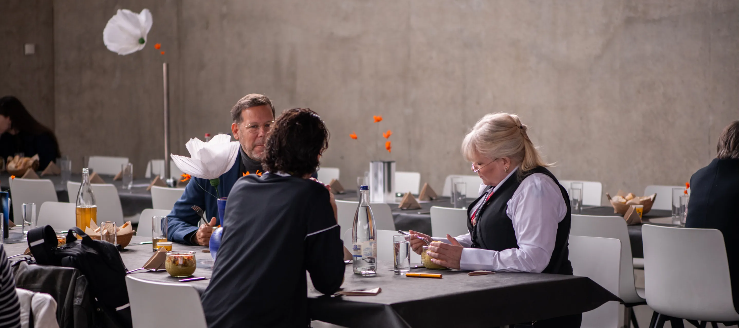 Trois personnes qui discutent à une grande table