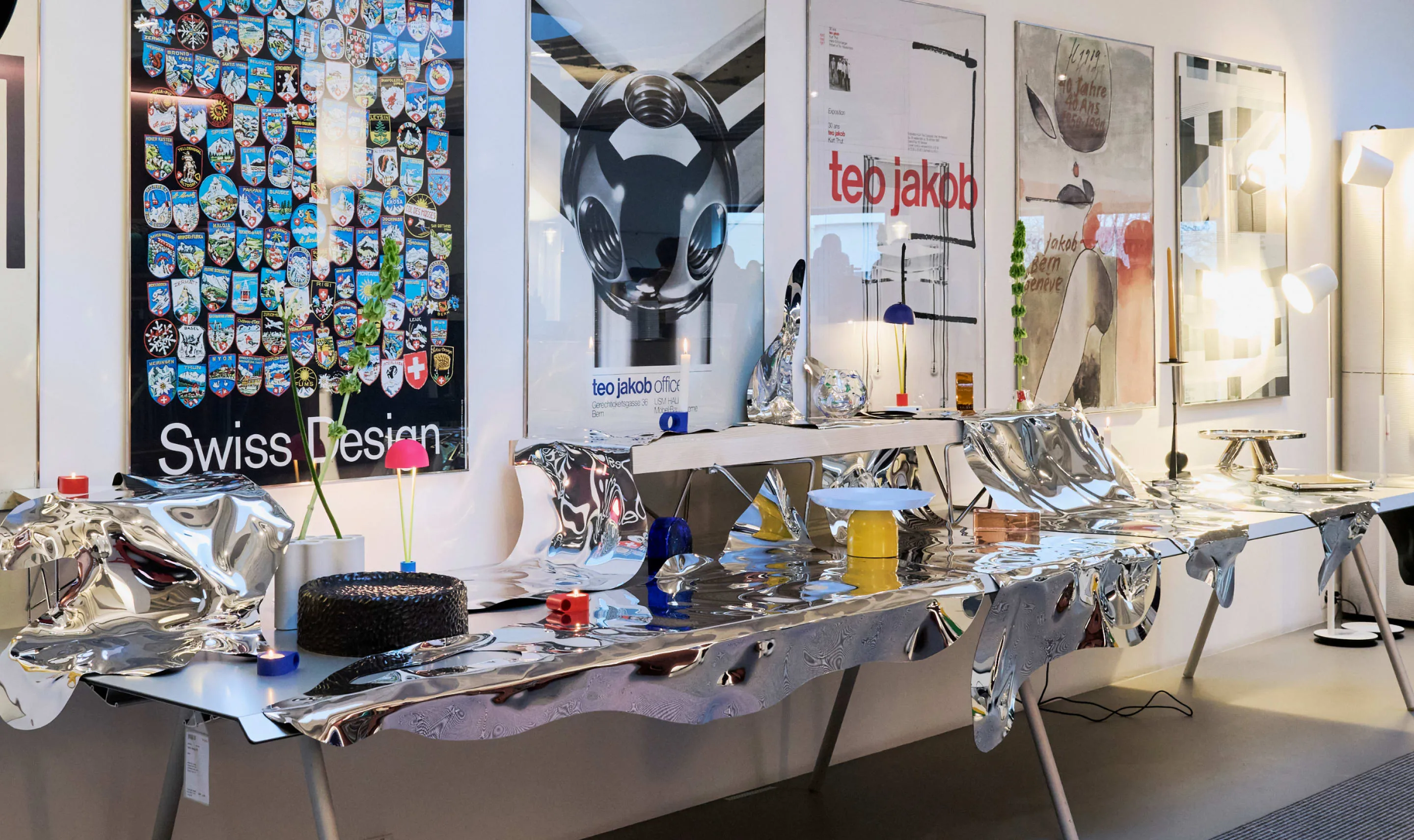Table recouverte de surfaces miroir thermoformées Pisoni–lab devant les affiches du showroom Teo Jakob