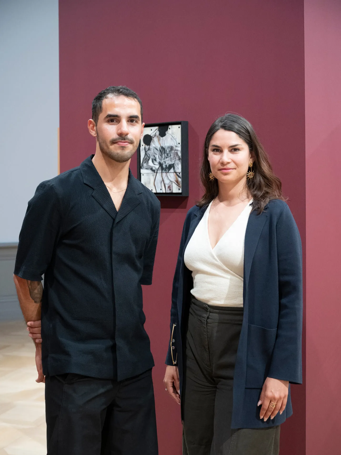 Karen Pisoni et Danniel Tostes devant une cimaise de l'exposition Communautés en résonance