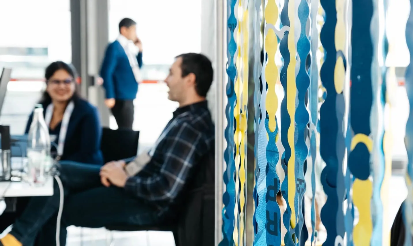Participants seated near a blue and yellow modular curtain