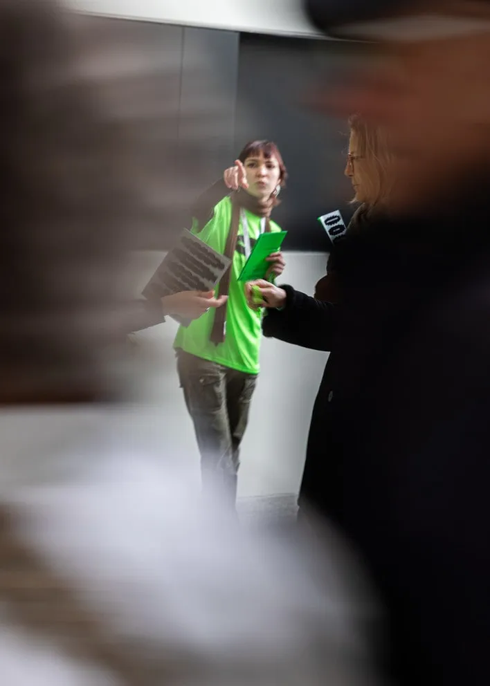 Personne en t-shirt vert accueillant les visiteur·euse·s, Portes ouvertes HEAD 2026