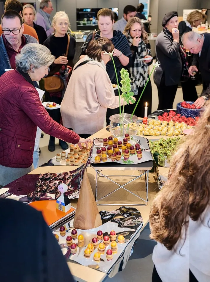 Invité·e·s se servant au buffet dressé sur des surfaces miroir, showroom Teo Jakob